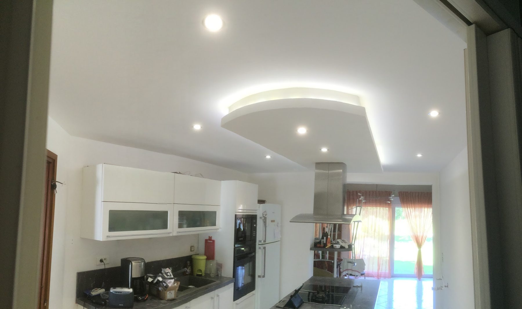 Cuisine avec faux plafond en vague éclairé par un ruban LED et des spots