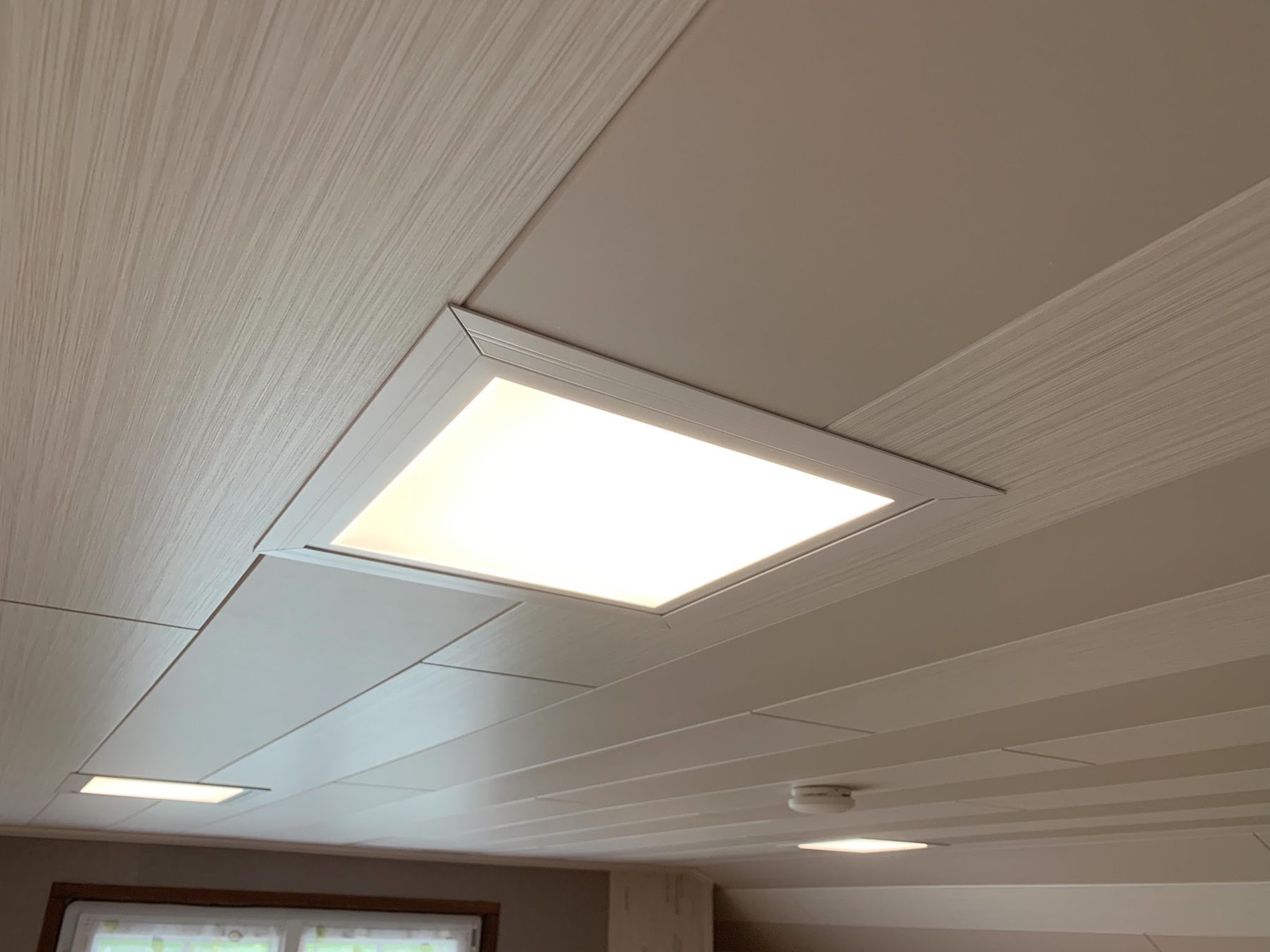 Dalle LED carrée encastrée dans un plafond en lambris